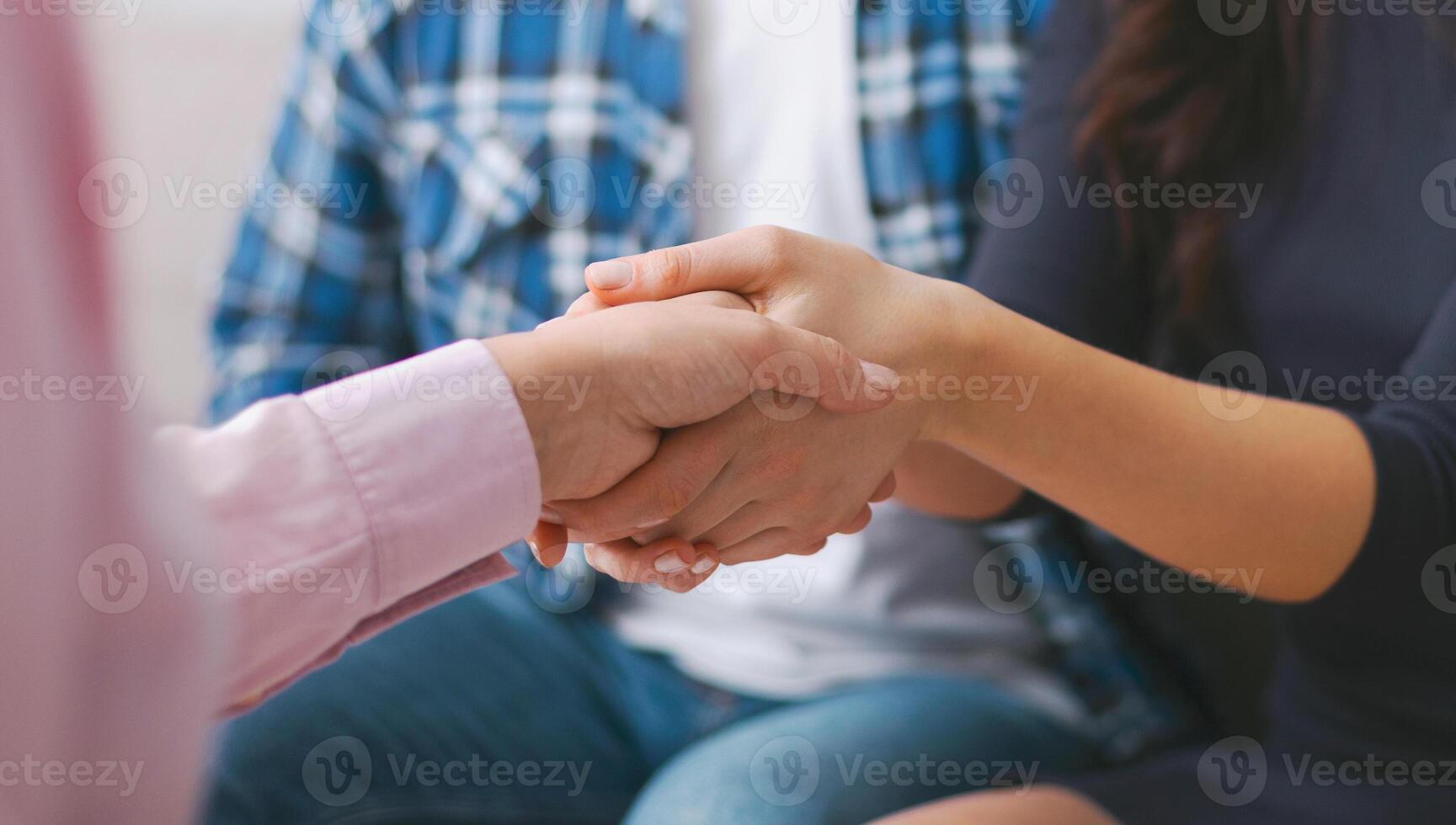 A close-up photo of two people shaking hands, likely during a group meeting or therapy session. The man and woman are wearing casual clothing and are focused on their handshake, cropped