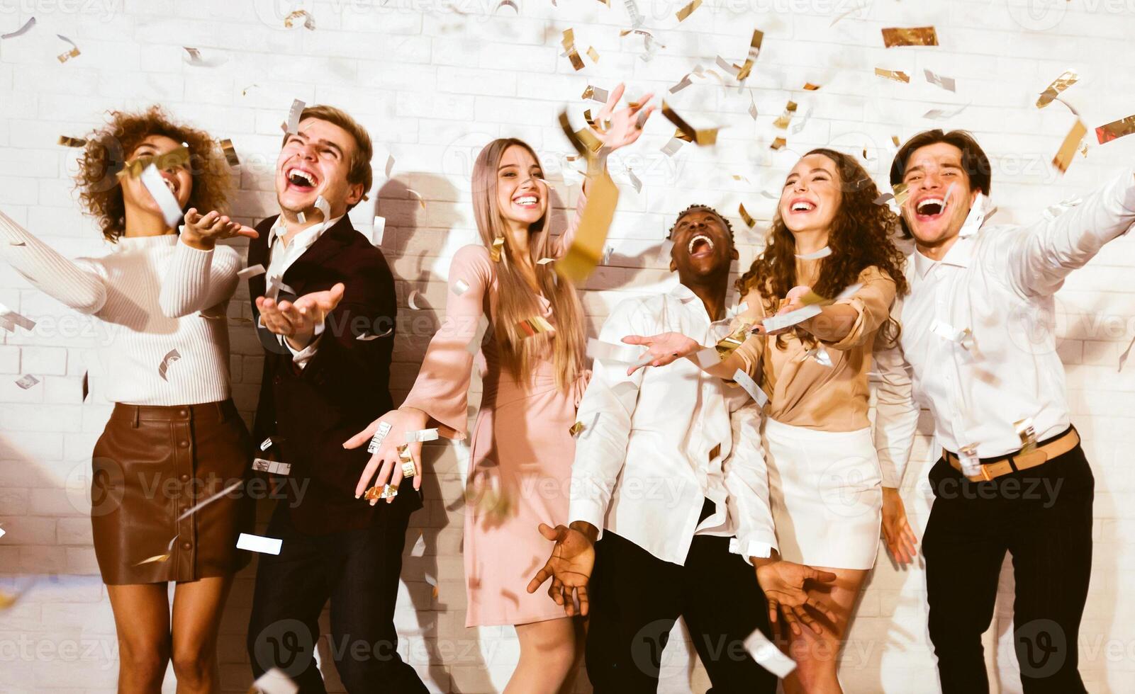 Young People Having Party With Falling Confetti Dancing And Having Fun Standing Indoors. Selective Focus photo