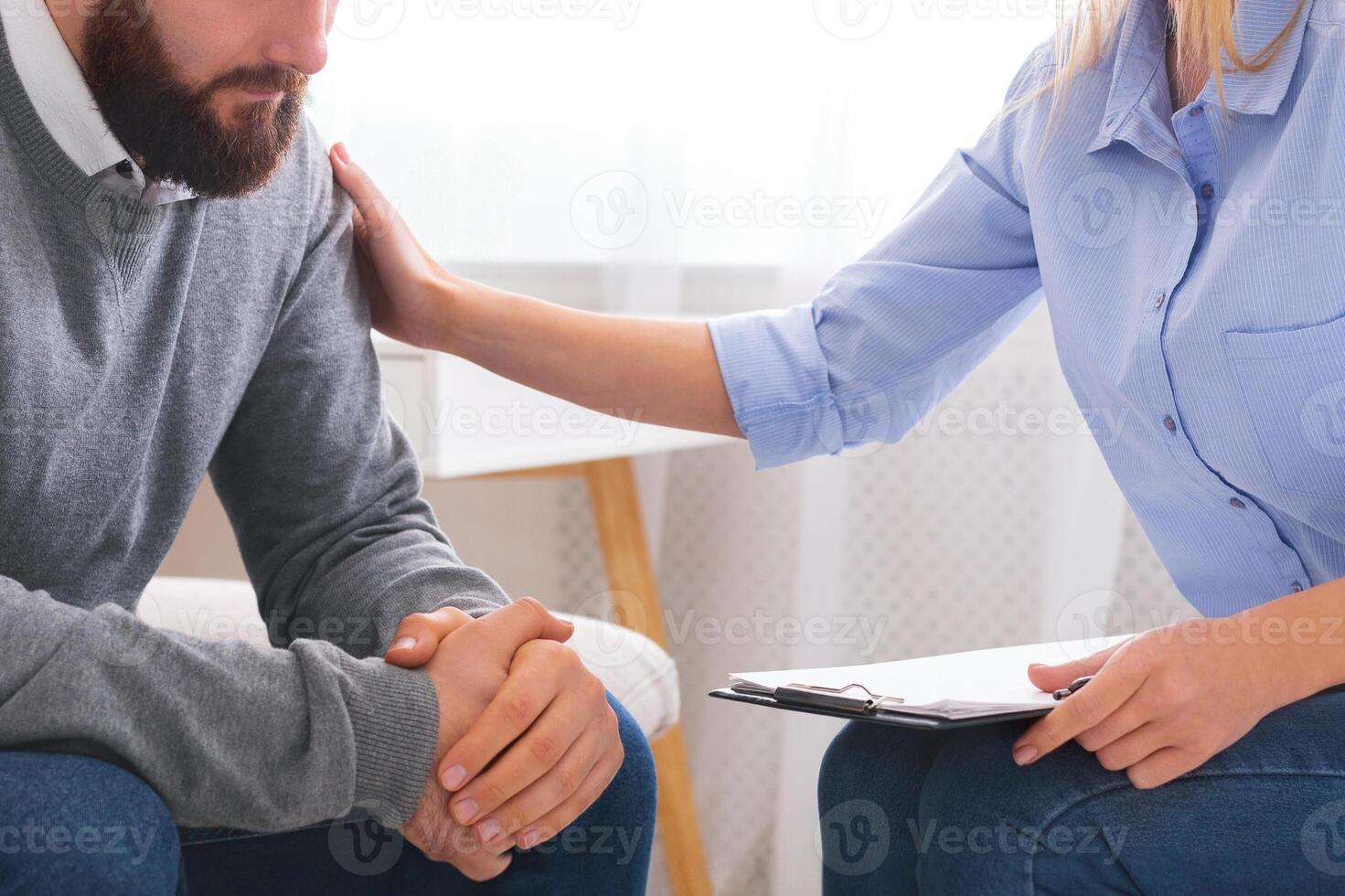 Professional psychologist comforting sad depressed male patient at personal consultation in office photo