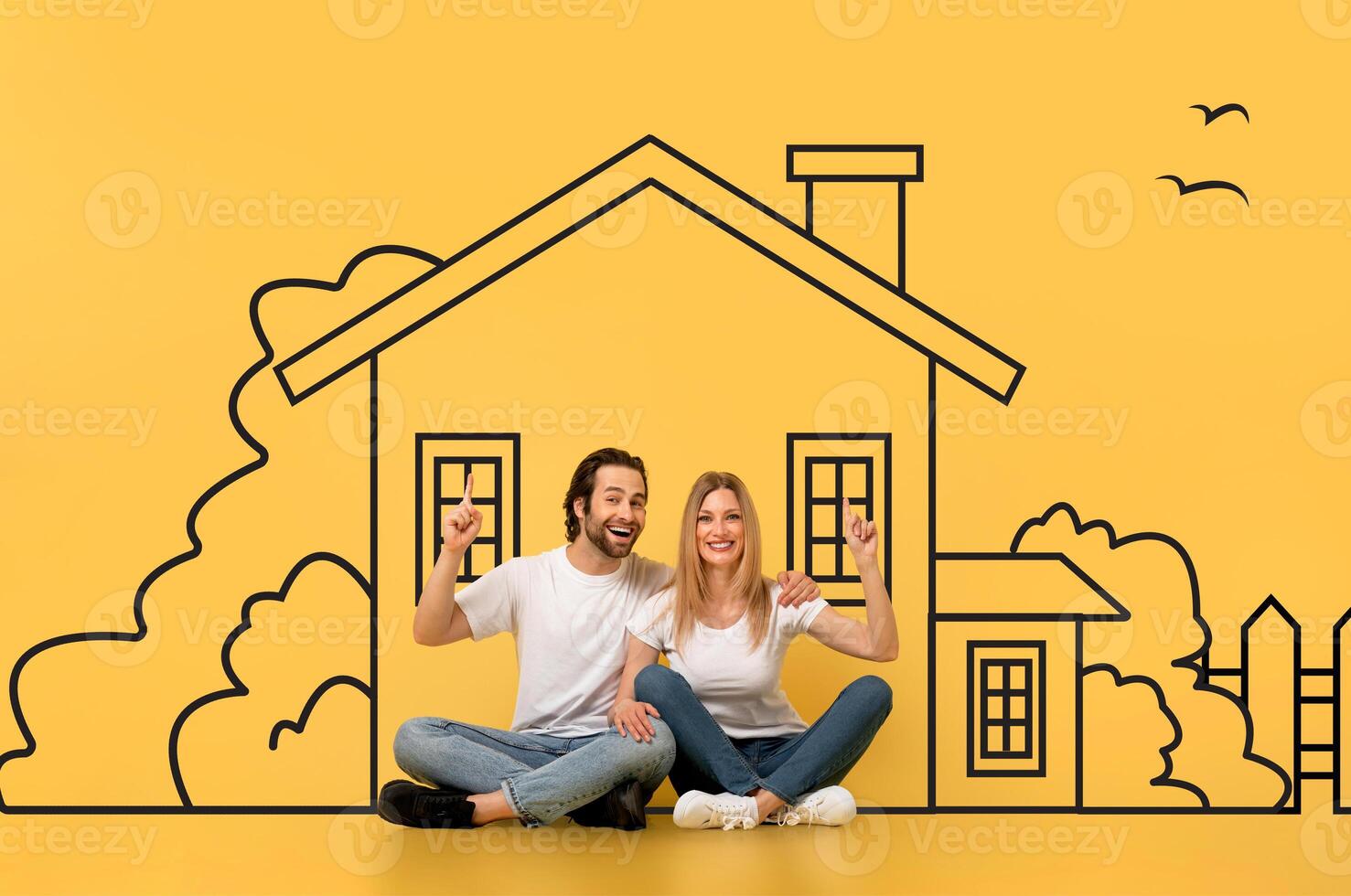 A man and a woman are seated on the floor, facing a large drawing of a house on a piece of paper. They appear to be studying the detailed features of the architectural design. photo