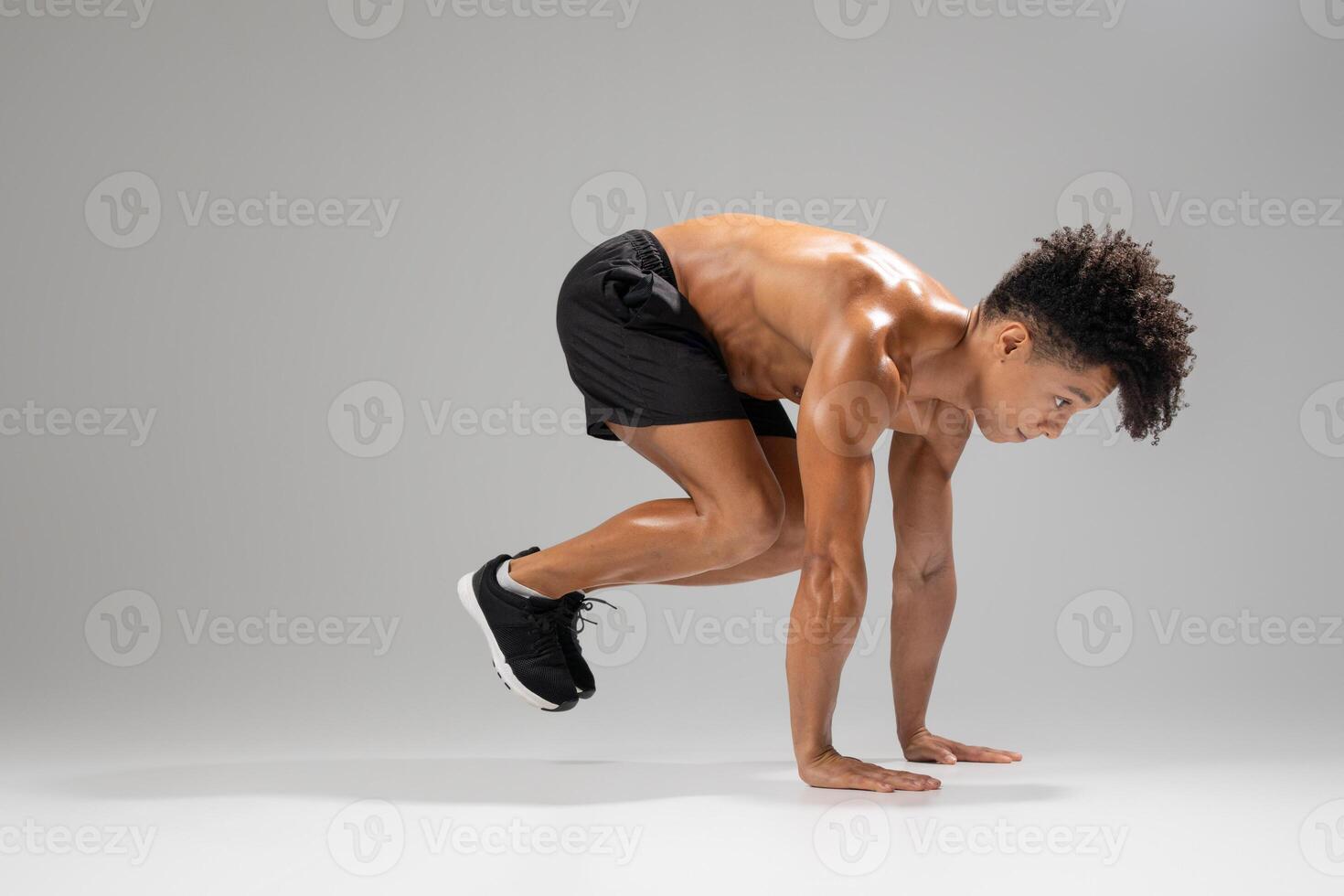 A fit young man engages in an athletic movement, focusing on strength and agility. He demonstrates a powerful stance in preparation for a dynamic workout, showcasing his dedication to fitness photo