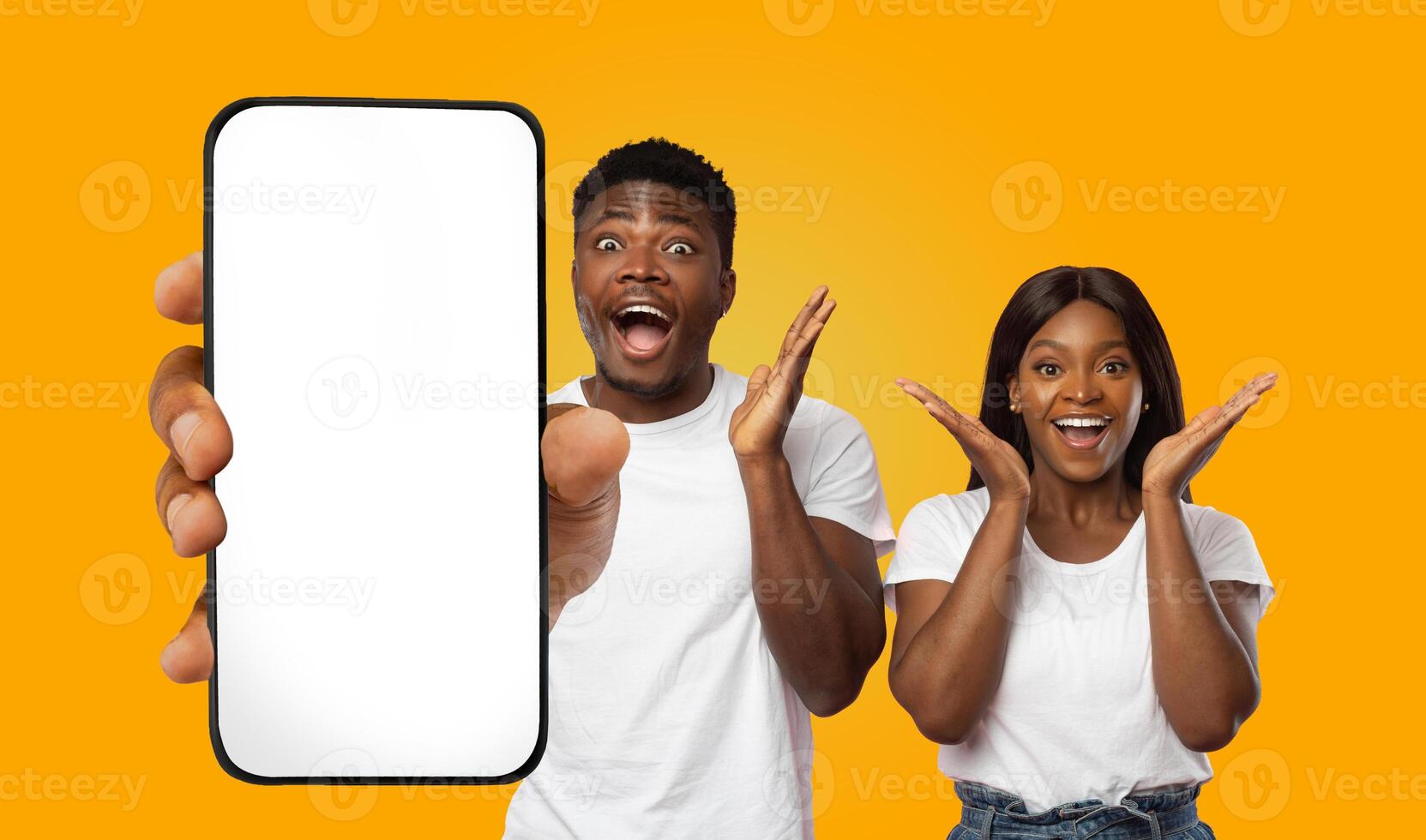 African American young man and woman are holding a smartphone with a blank screen. They are both smiling and looking excited. photo