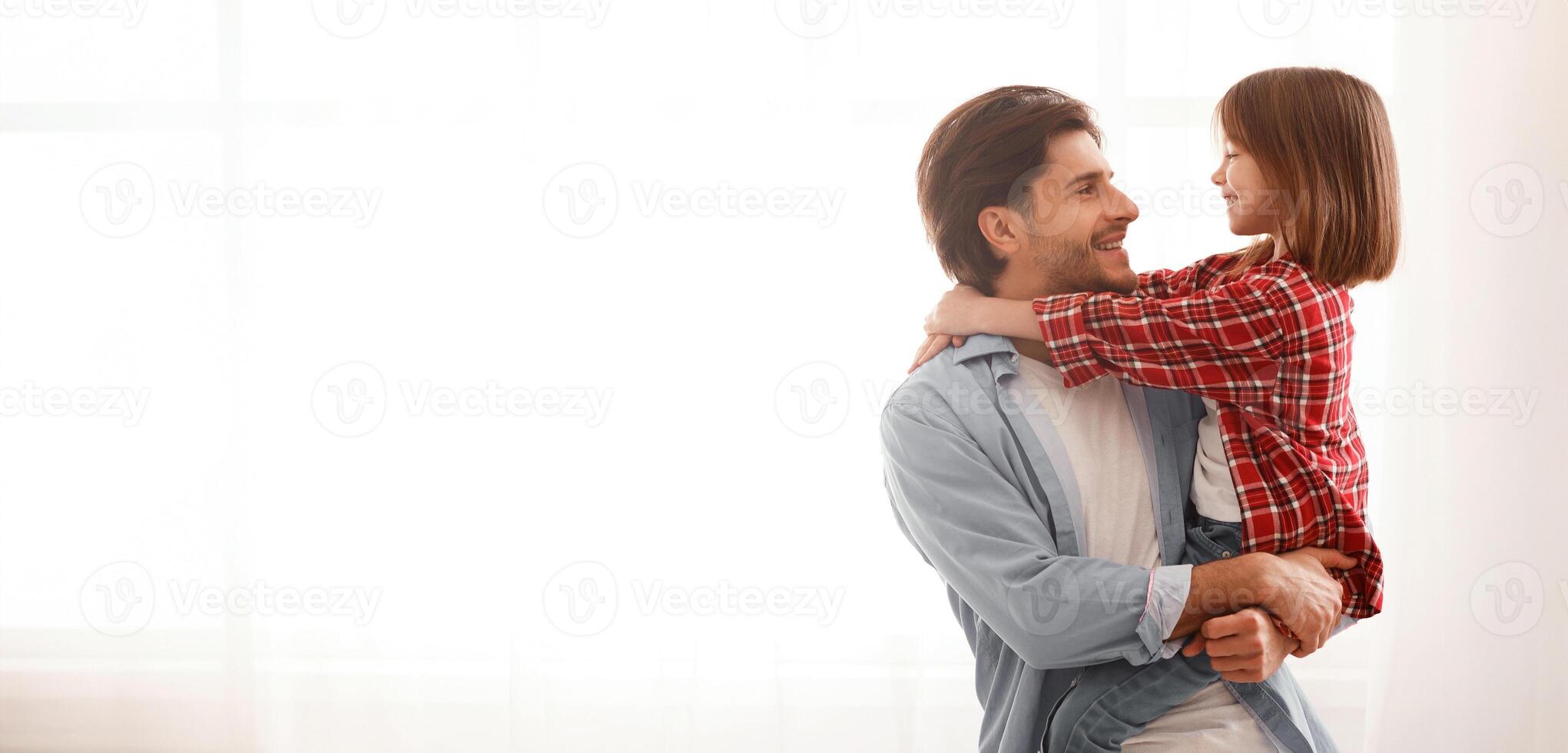 Handsome dad holding his cute daughter, looking at each other, window background, panorama with copy space photo