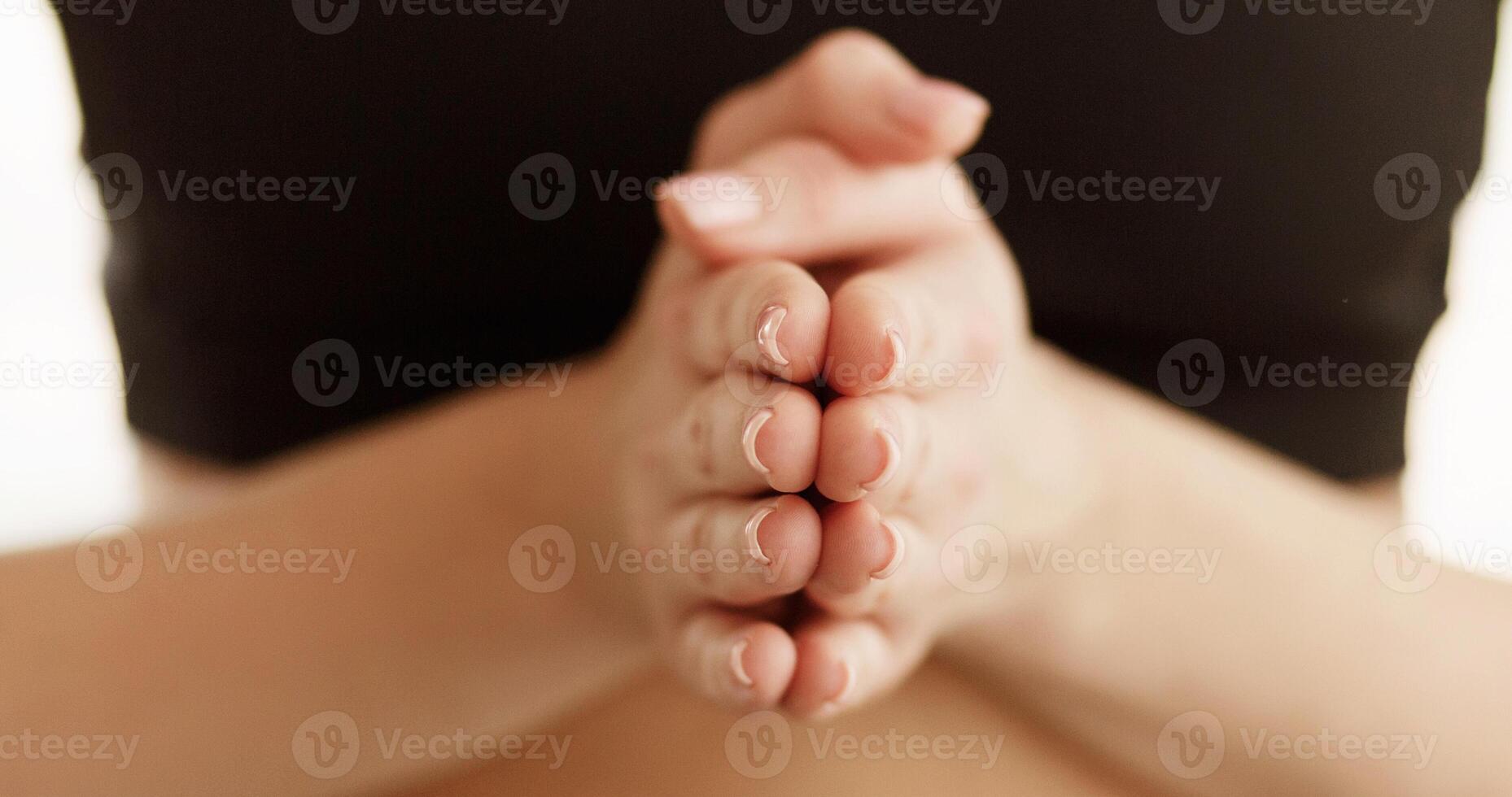 Cropped of sporty woman holding hands clasped tightly together, fingers intertwined, showing a gesture of unity or concentration. photo