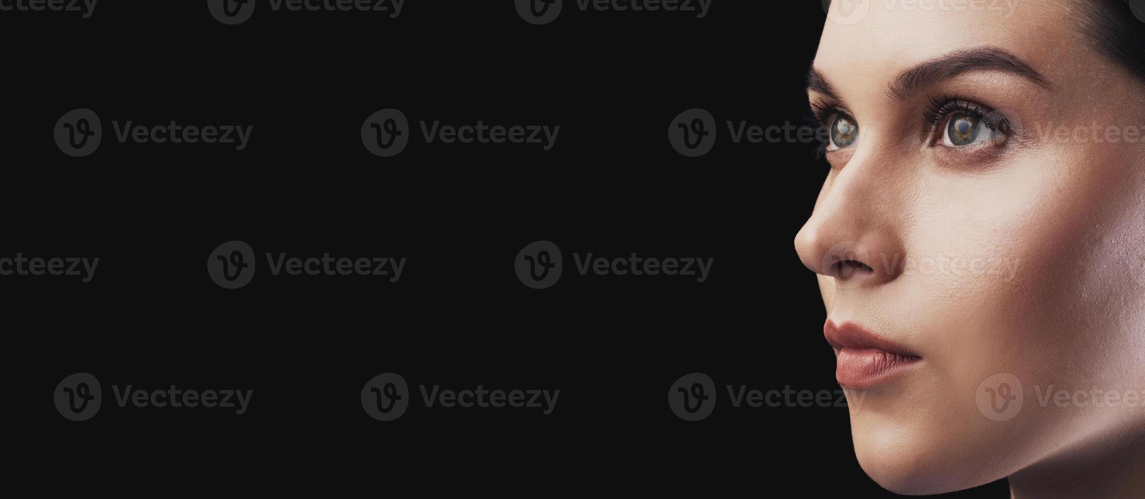 A close-up shot of a womans profile against a dark background. She is looking off to the side with a serious expression. photo