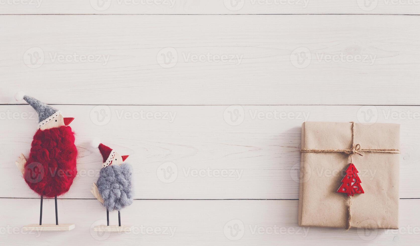 Christmas background with copy space. Top view of gift boxes and funny birds toys. Presents in craft paper with red ribbon bows and spruce tree on white wood. Celebration of winter holidays concept photo