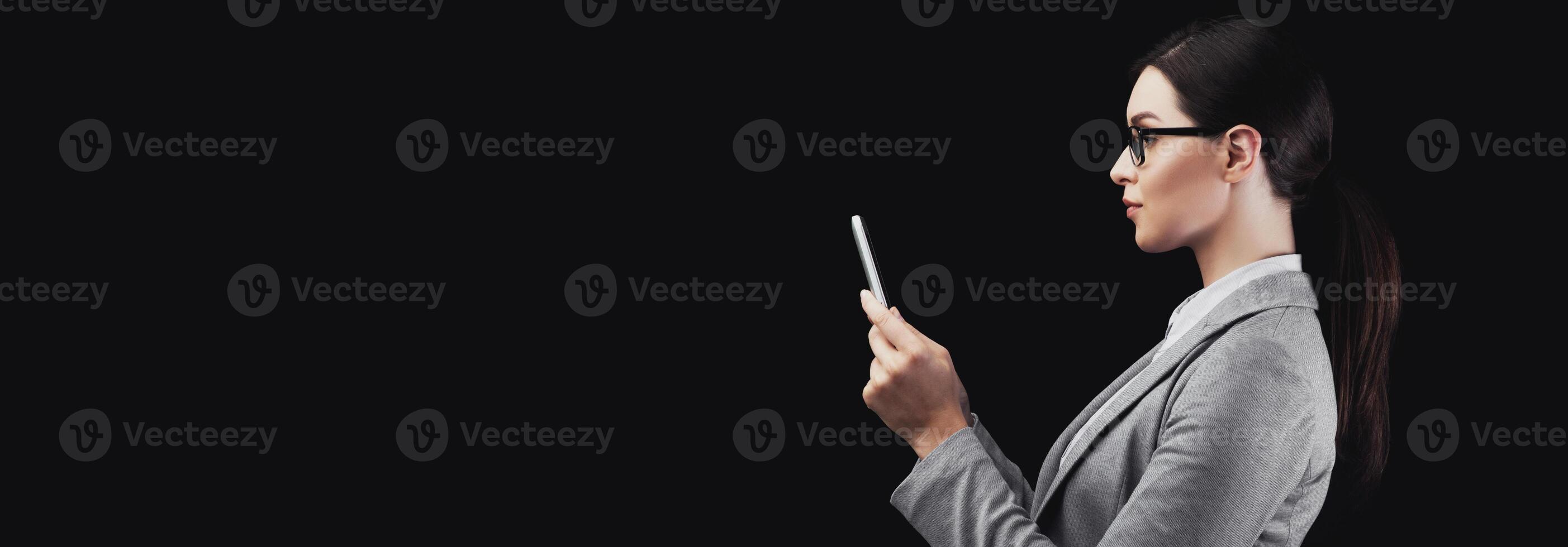 Face ID Recognition. Young Businesswoman Using Smartphone Biometric Verification System On Black Background. Studio Shot, Side View photo