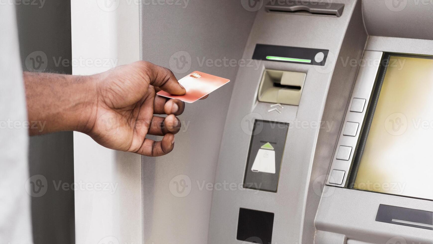 A persons hand inserts a credit card into an ATM machine. photo