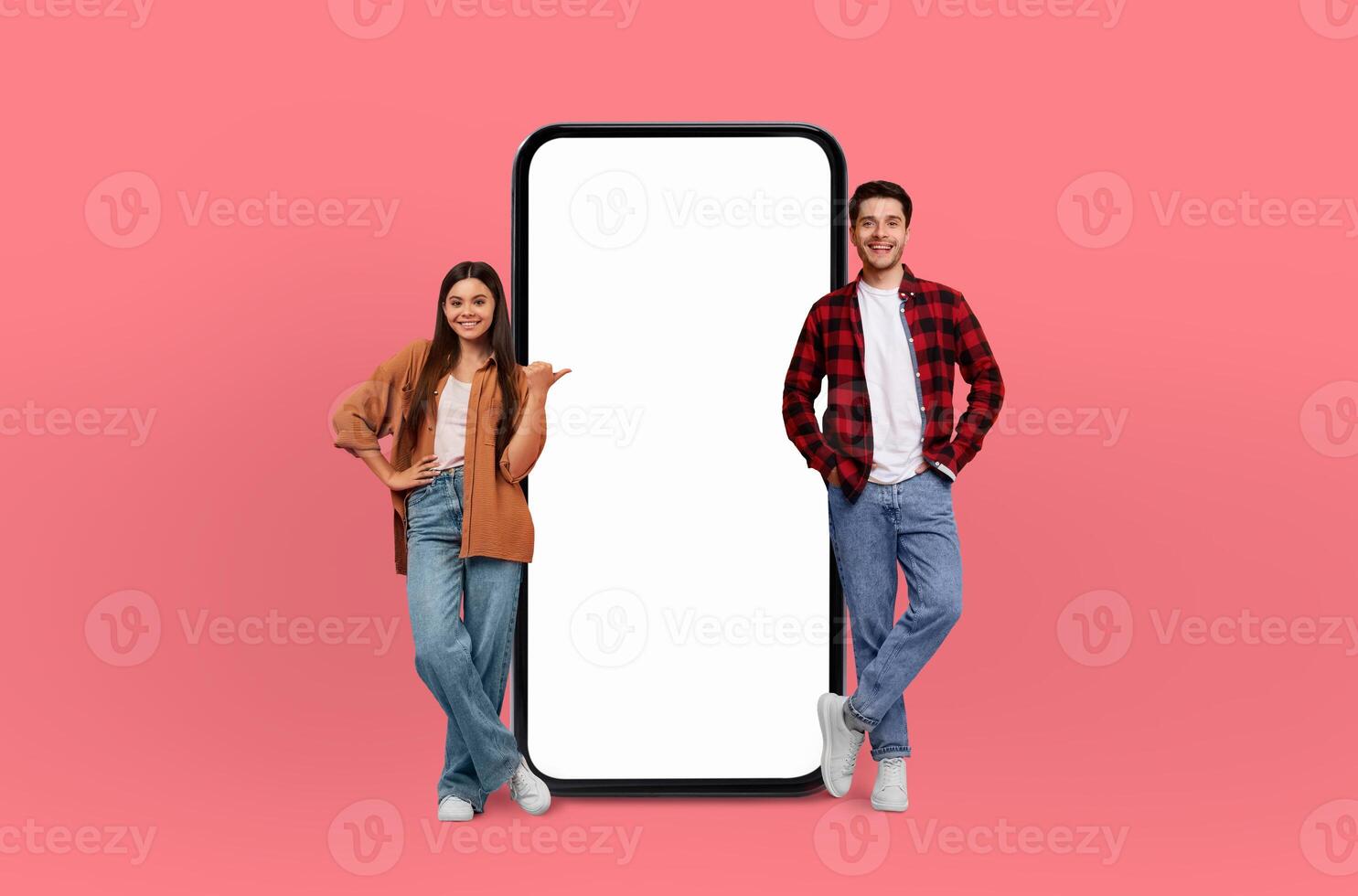 The smartphone beside them, with its screen unmarked, complements the vibrant energy and diverse backgrounds of the smiling young couple. photo
