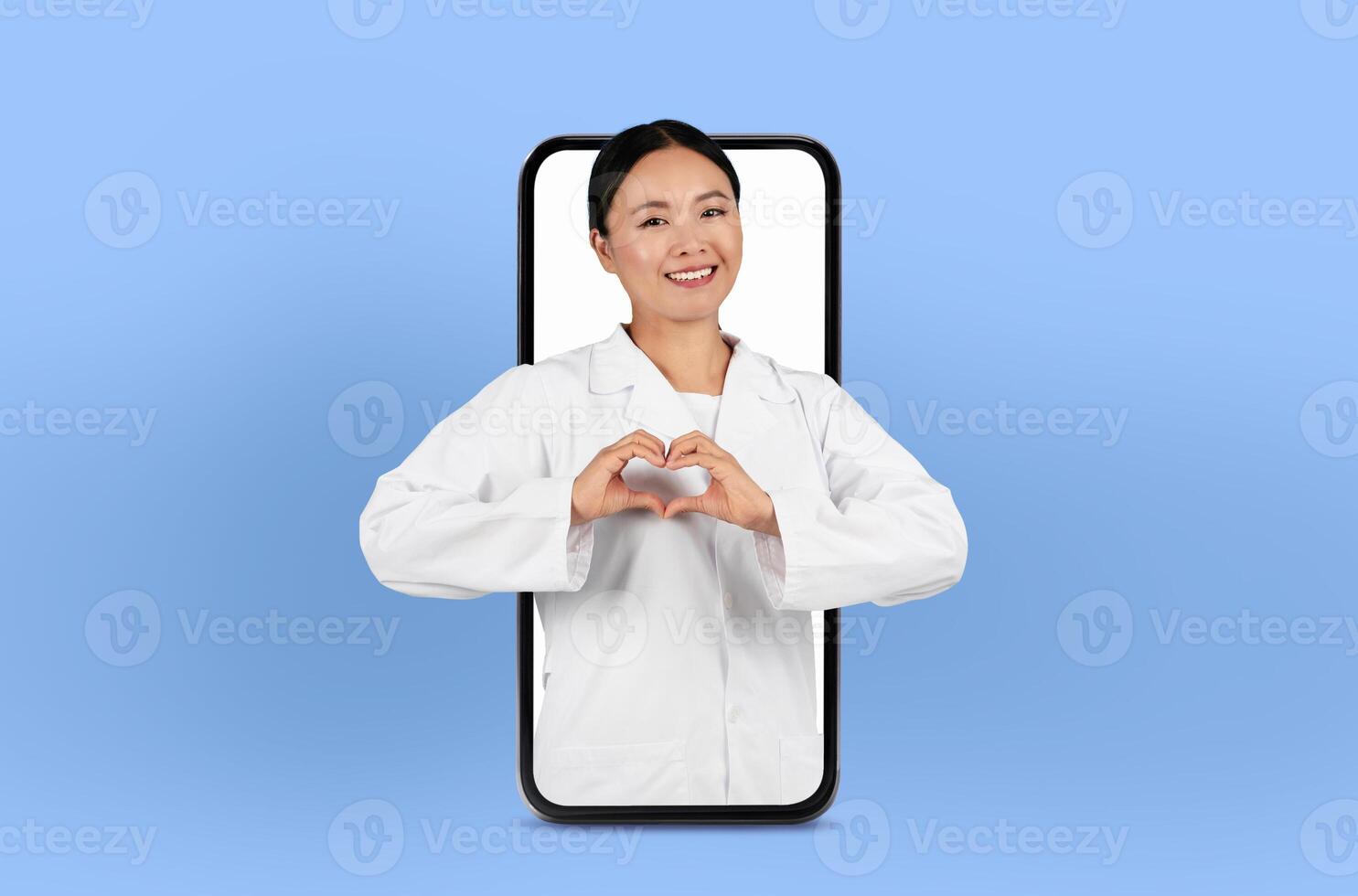 Asian lady physician offers remote consultation, visible on a smartphone screen, surrounded by soft lighting, showing heart gesture photo