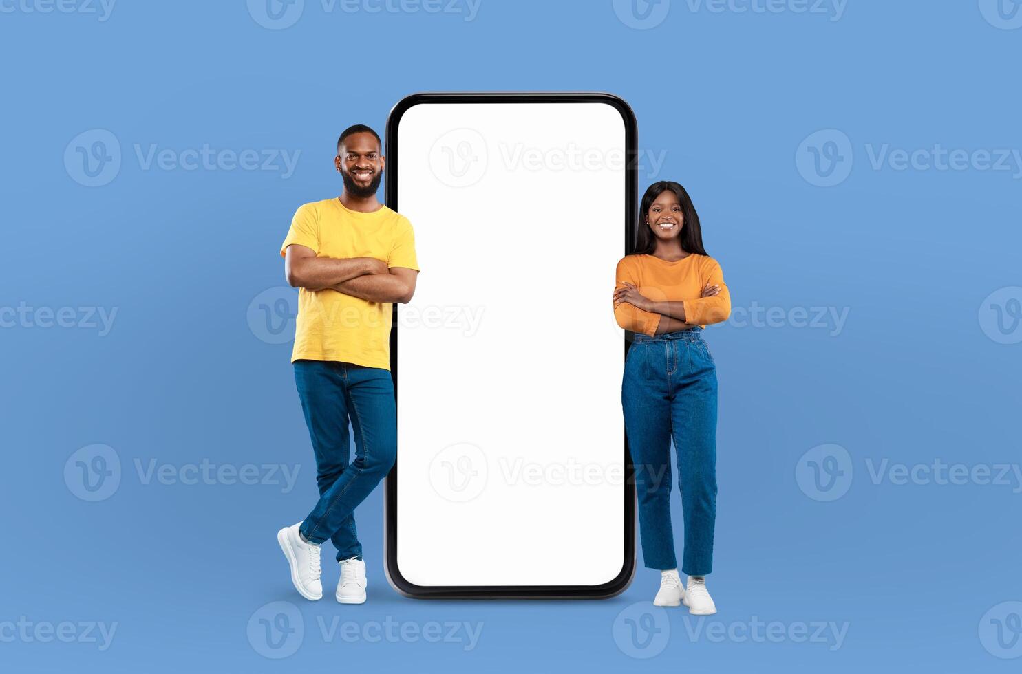 Black couple positioned next to a blank screen while standing against a blue background. They appear to be engaged in a presentation or discussion, with the screen ready for content to be displayed. photo