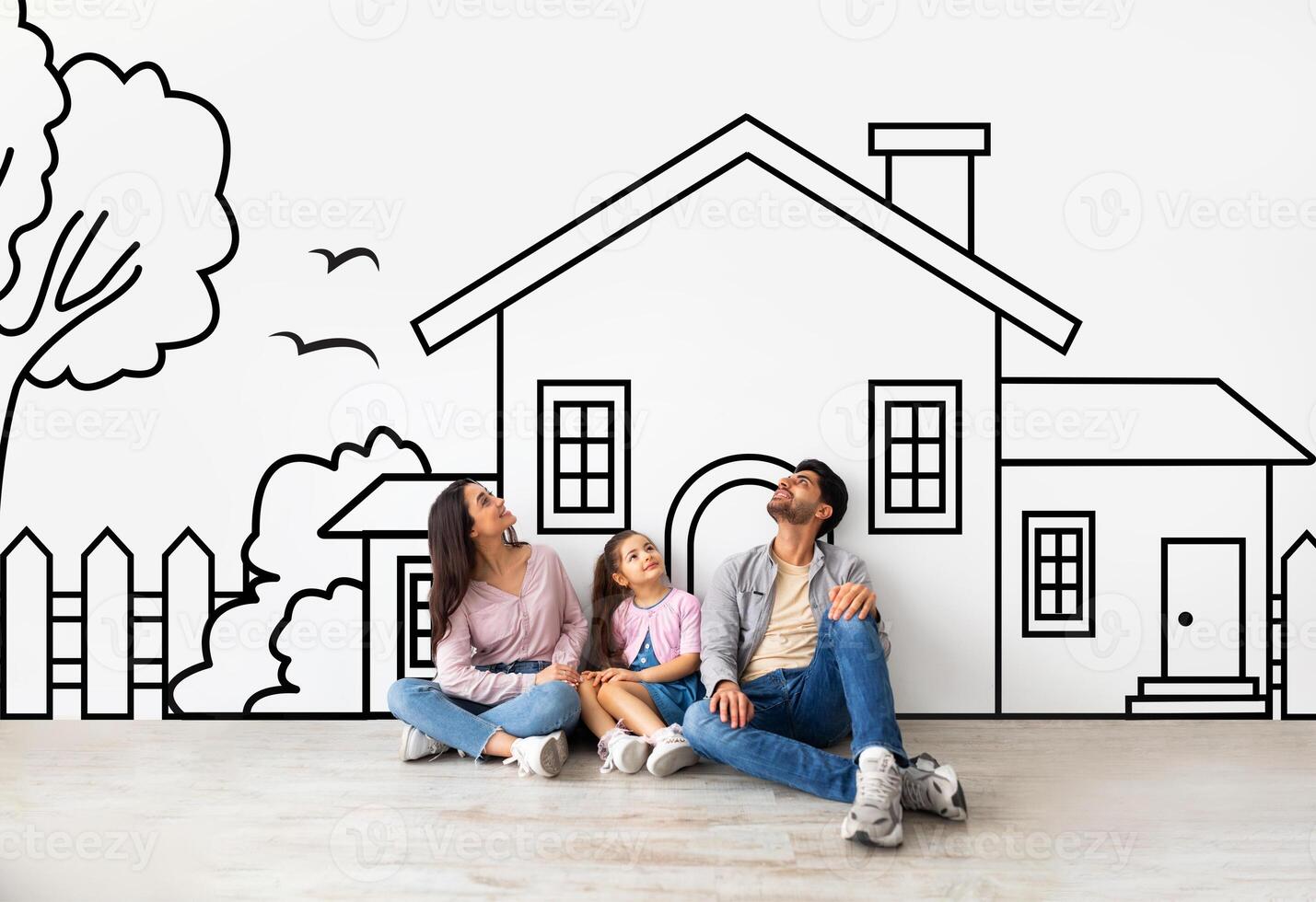 Middle eastern family father mother and daughter sitting over drawn on white wall house, looking up and smiling. Real estate, mortgage concept photo