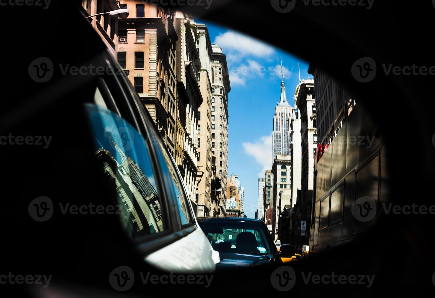 A car mirror showing a city street with buildings in the background photo