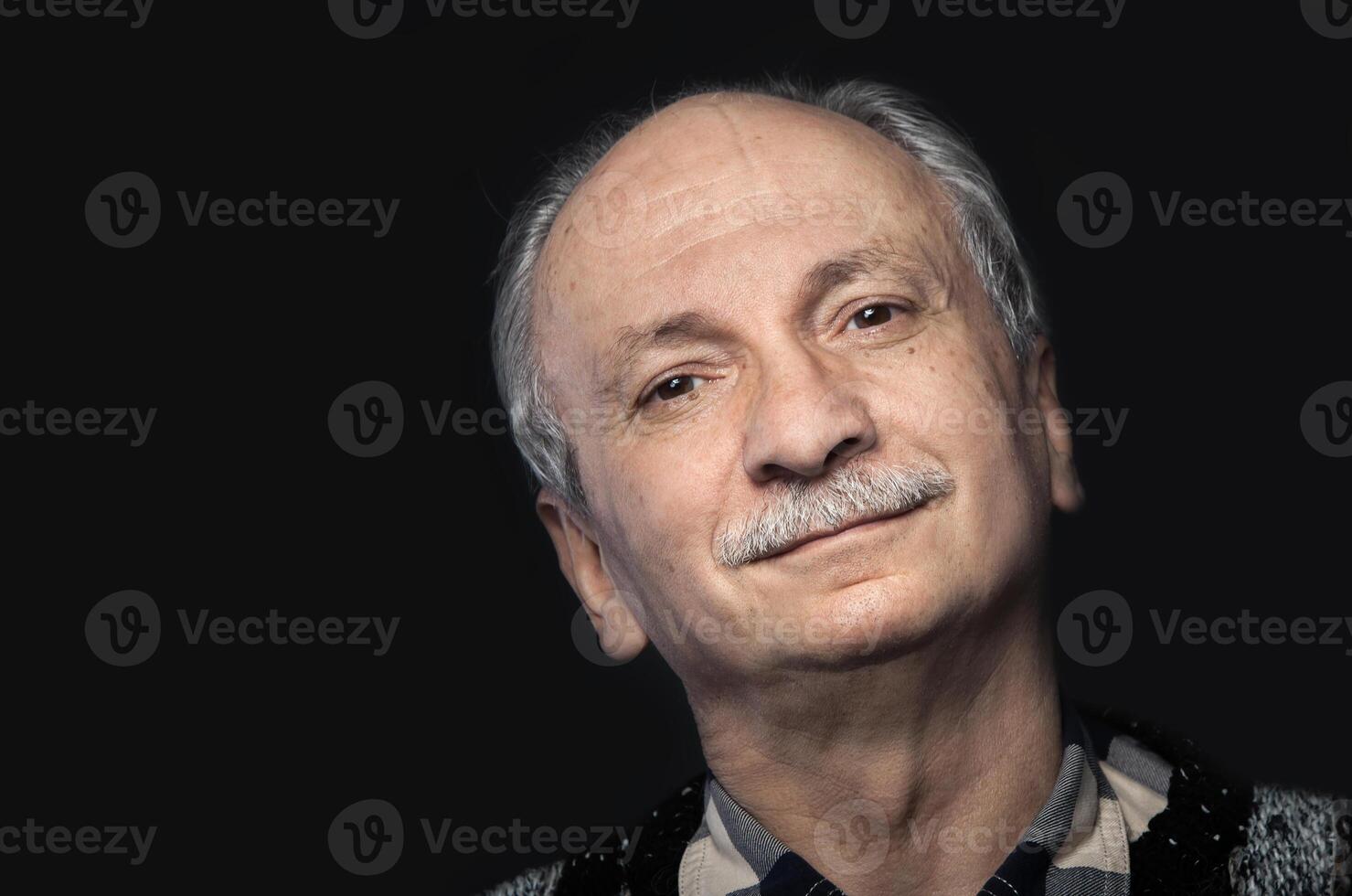 An older man with a mustache and a sweater photo