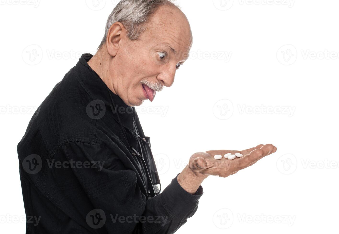 An older man holding a pill in his hand photo