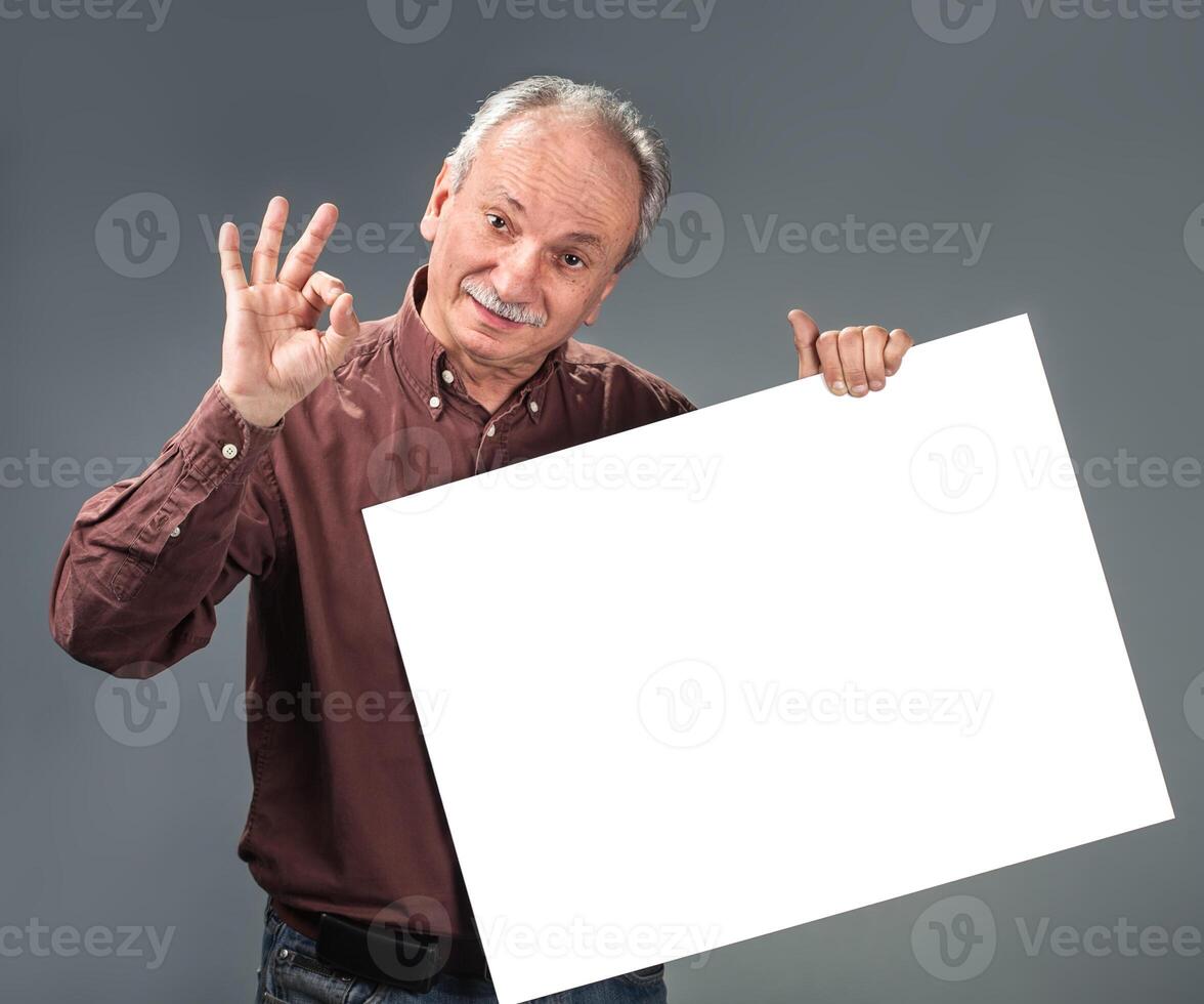 An old man holding up a blank sign photo