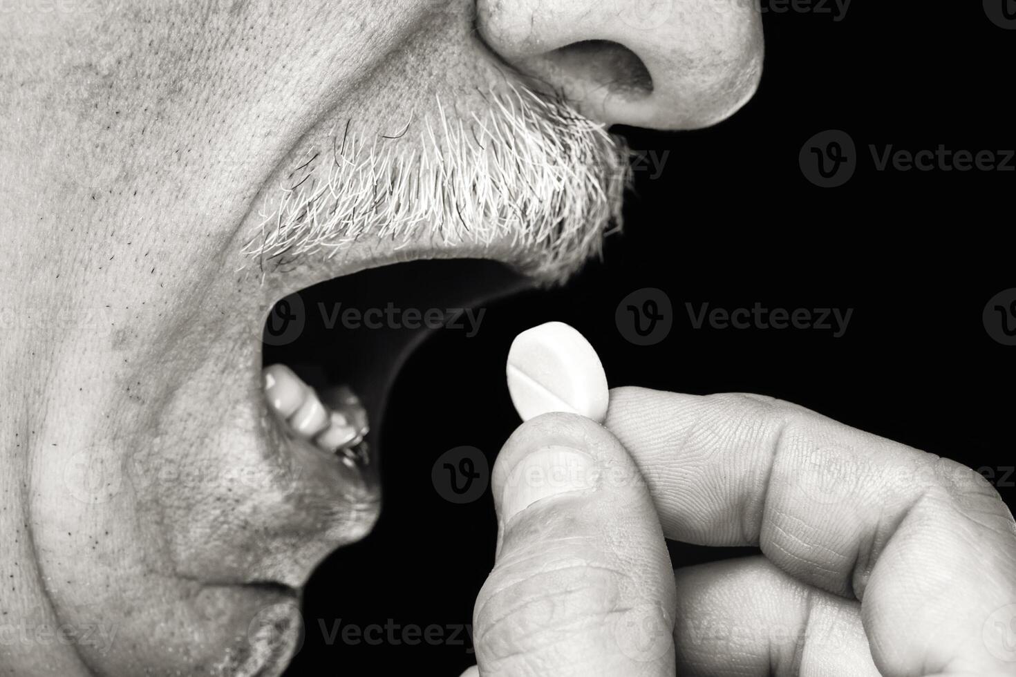 A man taking a pill from his mouth photo