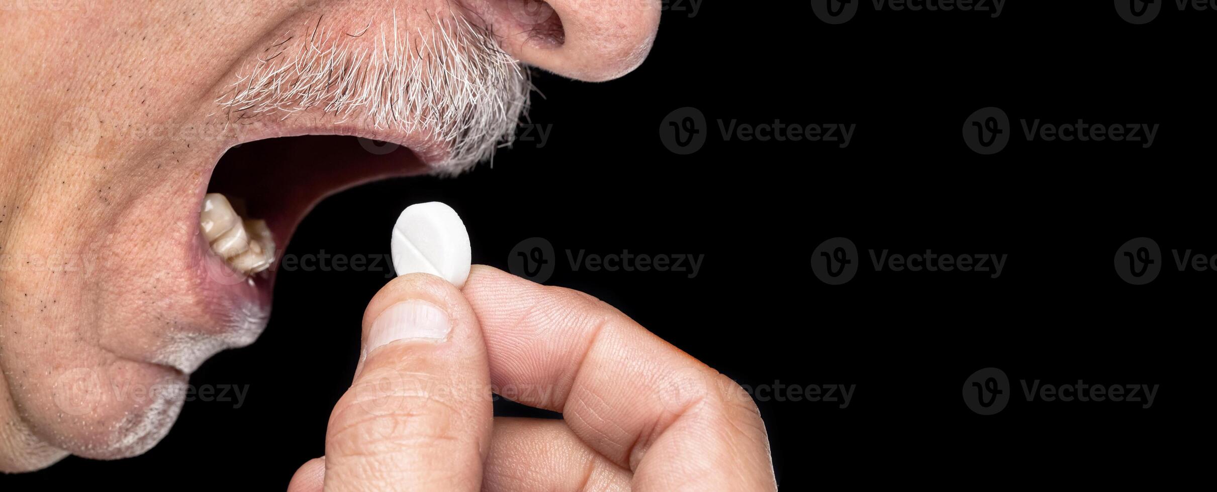 A man taking a pill from his mouth photo