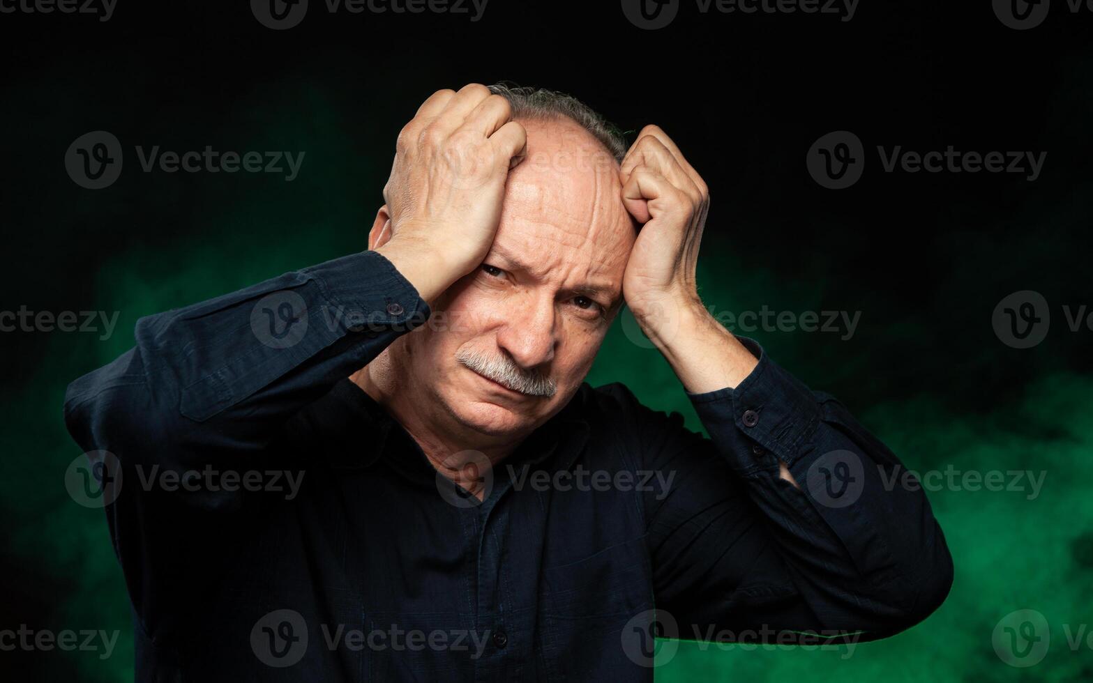 An old man with his hands on his head photo