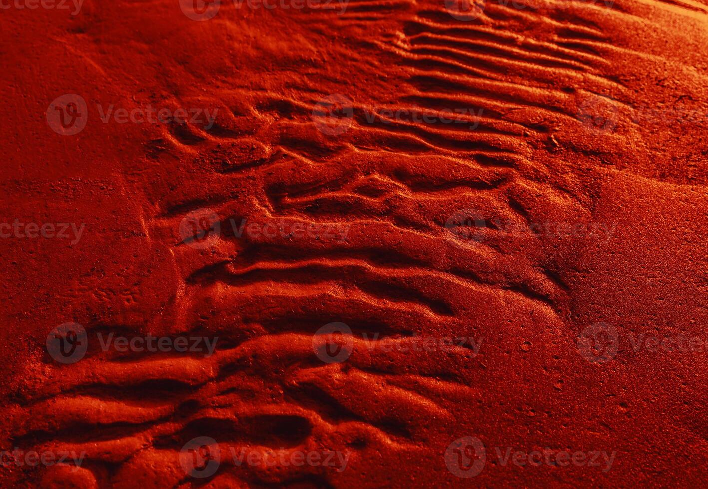 A red sand surface with footprints in it photo