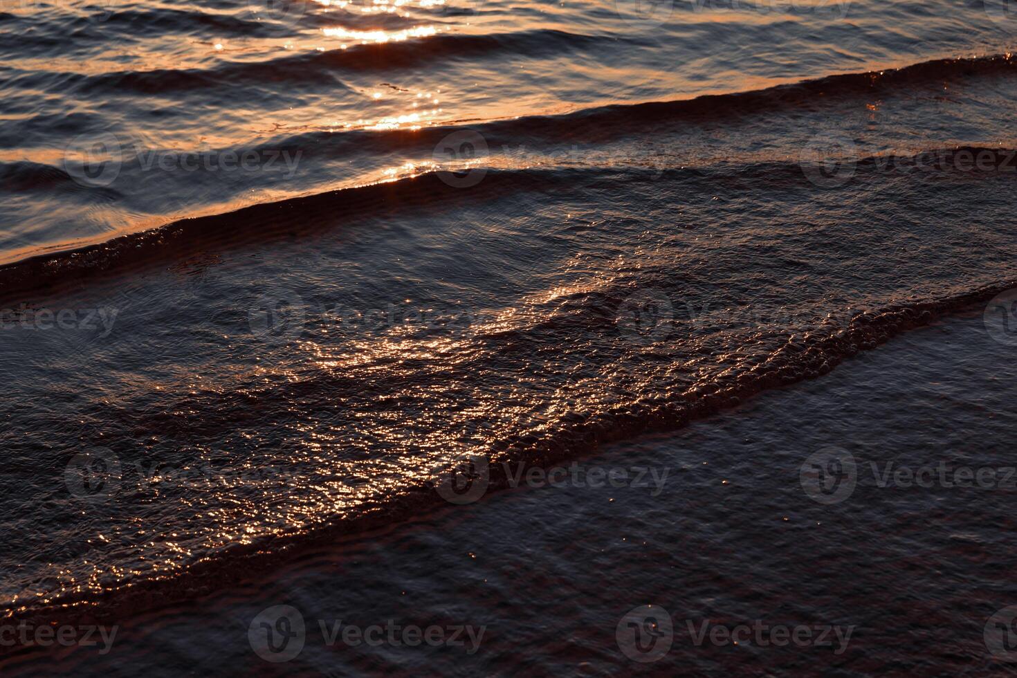 A person on a surfboard riding the waves at sunset photo
