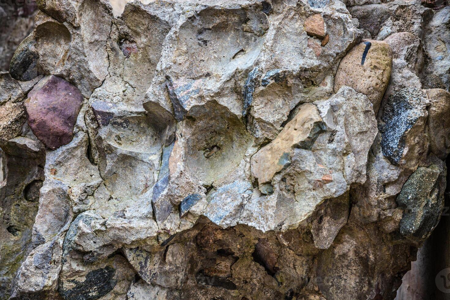 A large rock wall with many different colored rocks photo