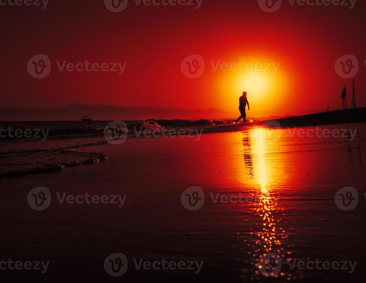 A person walking on the beach at sunset photo