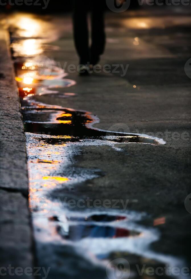 A person walking on a sidewalk with a reflection of the street photo