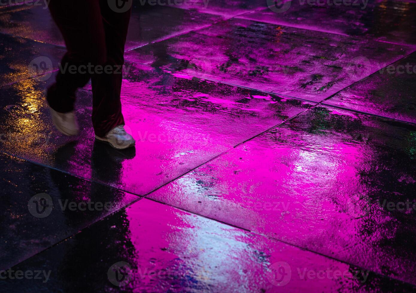 A person walking on a wet sidewalk photo