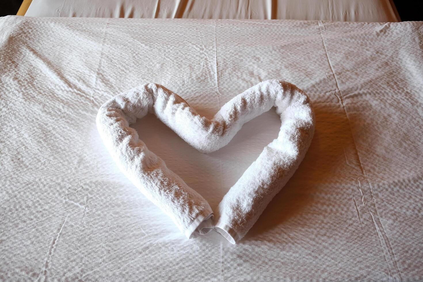 Close up white heart shaped towel is placed on the bed in the resort room for honeymoon trip of couple marriage for destination travel on valentine holiday photo