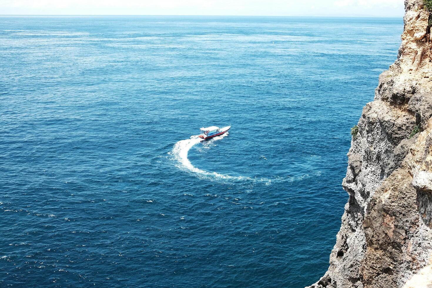 Speed boat with wave crashing rocky cliff at the blue sea and destination travel summer ocean in Bali island at Indonesia photo
