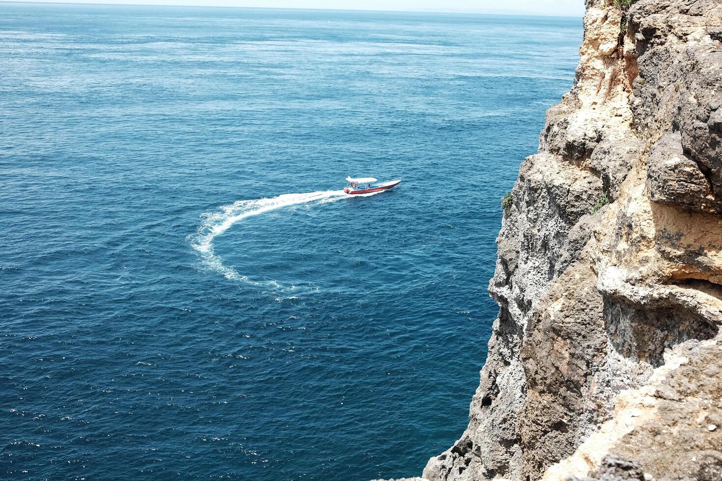 Speed boat with wave crashing rocky cliff at the blue sea and destination travel summer ocean in Bali island at Indonesia photo