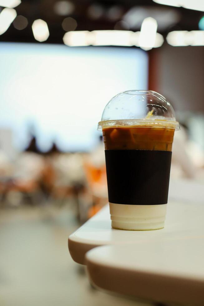Close up glass of ice latte with blurred people in business workshop and presentation.Beverage at the conference room. photo