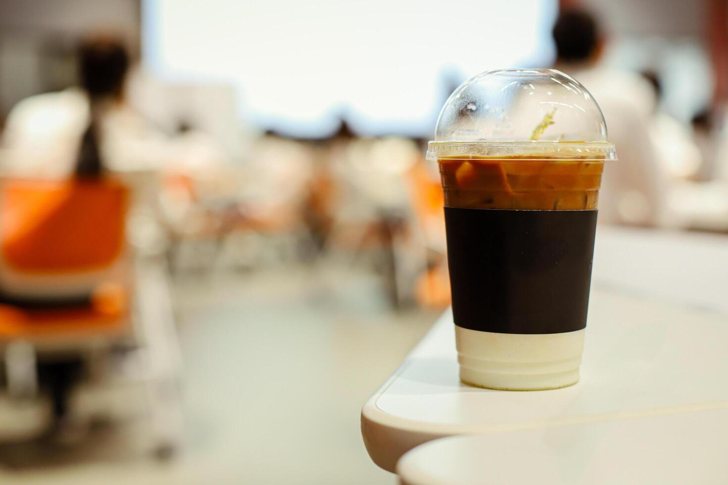 Close up glass of ice latte with blurred people in business workshop and presentation.Beverage at the conference room. photo