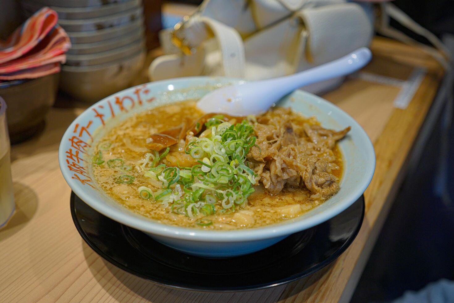 Close up ramen soup with noodles and meat in white bowl at ramen restaurant. photo