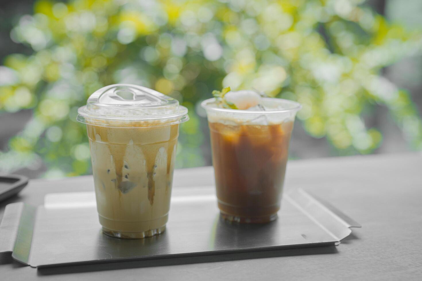 Close up glass of ice black coffee with lychee juice and ice cappucino on raw cement table of a coffee shop summer terrace, menu photography. photo