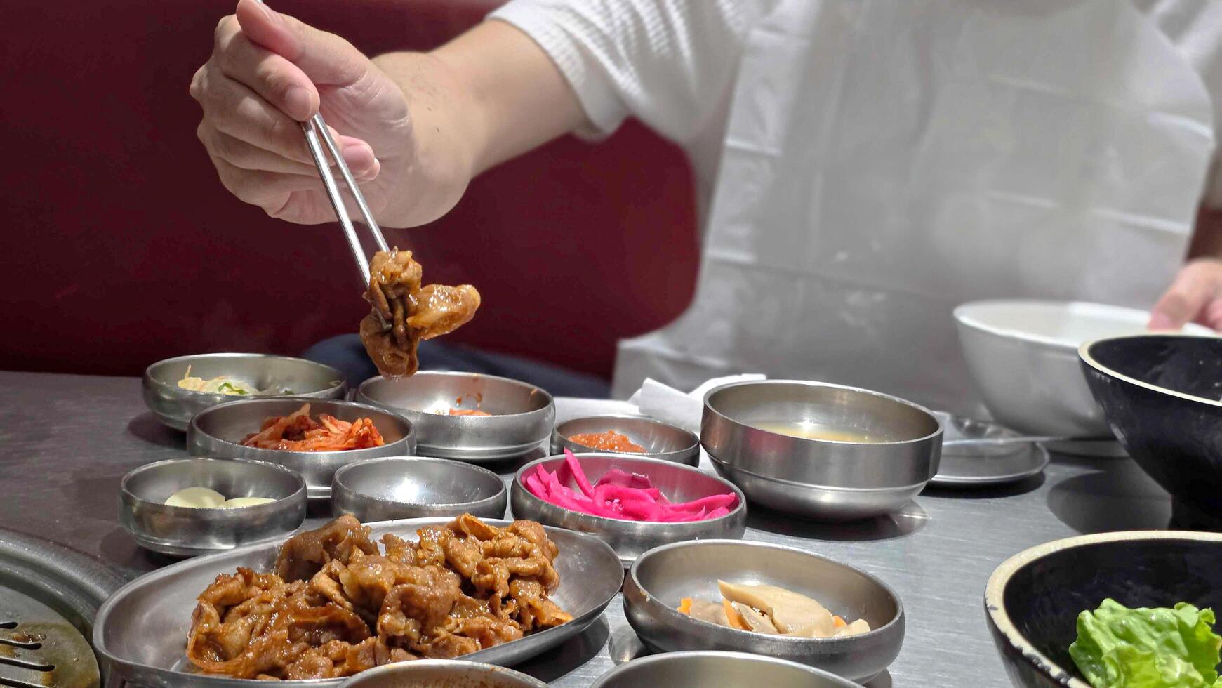 Crop anonymous man with chopsticks eating yummy Yeoltan Bulgogi and meat in gray bowl at Korean restaurant. photo