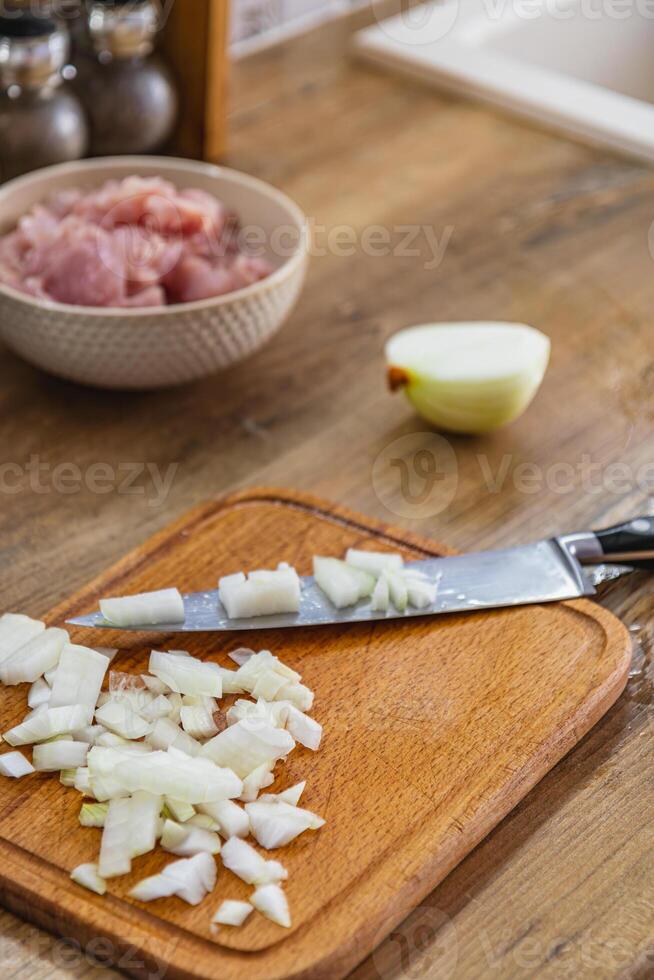 Finely chopped onion, chicken fillet in a bowl on the side photo