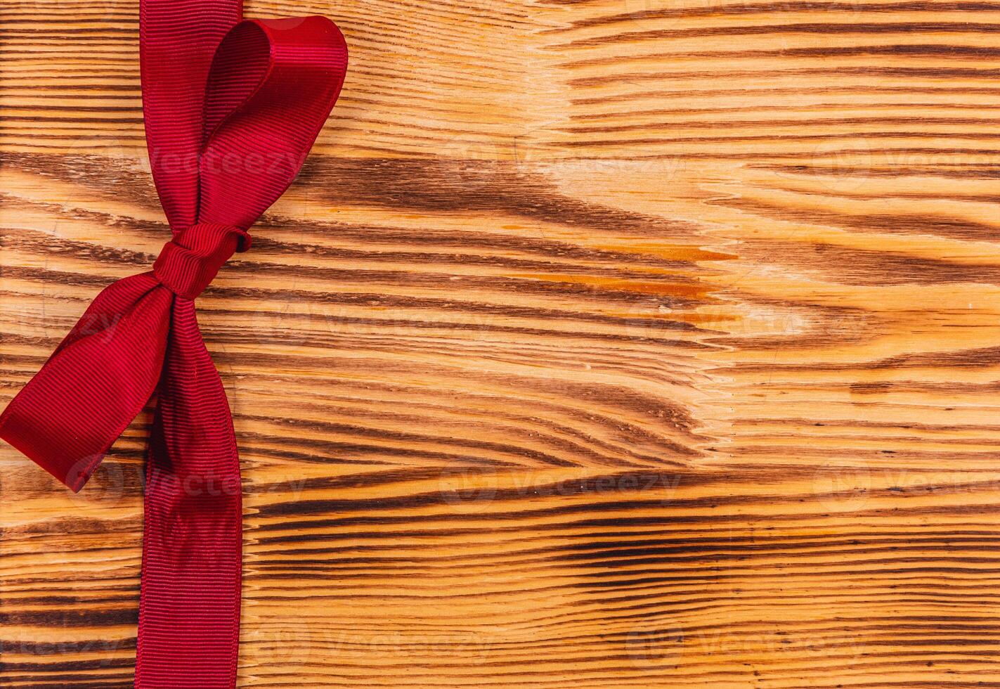 Dark red ribbon and bow on a beautiful wooden background photo