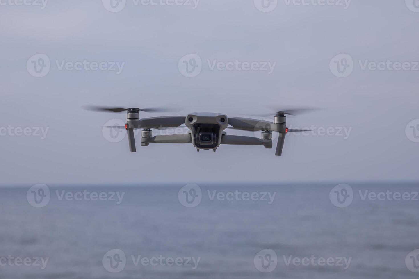 a gray drone flies in the sky over the sea photo
