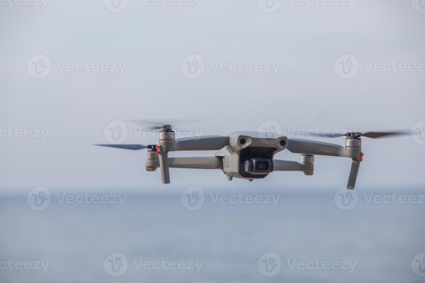 a gray drone flies in the sky over the sea photo
