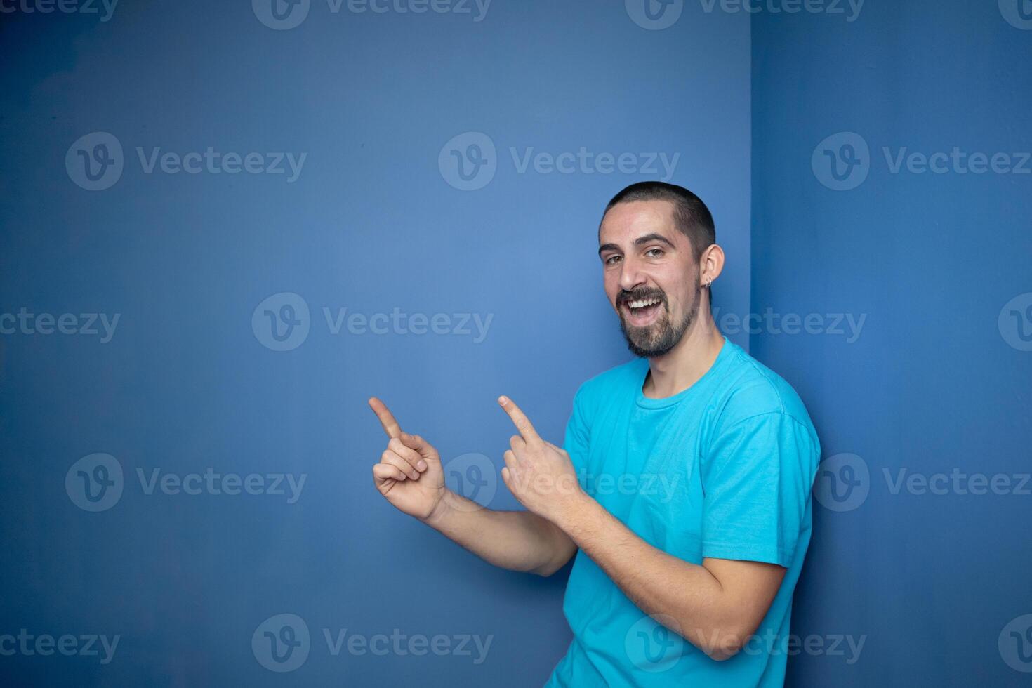 Young man pointing empty space using hands and fingers, isolated over blue background photo