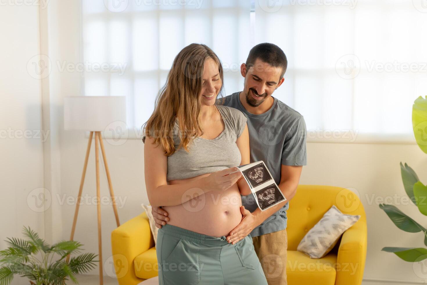 Pregnancy couple looking picture of ultrasound, smiling happily touching belly photo
