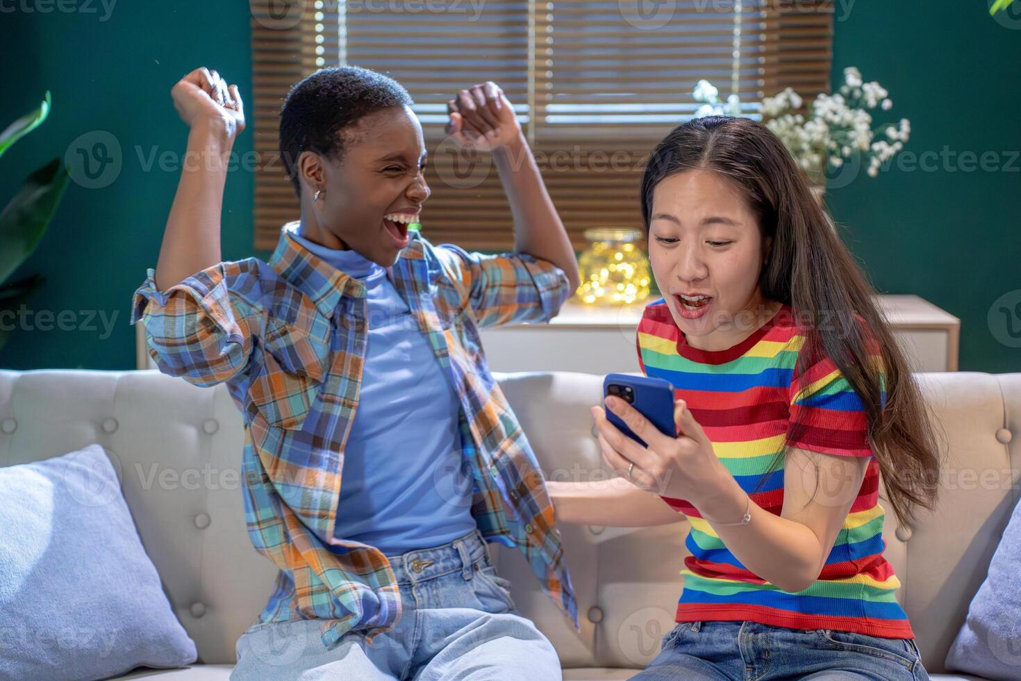 Two women friends laughing celebrating with cell phone. photo