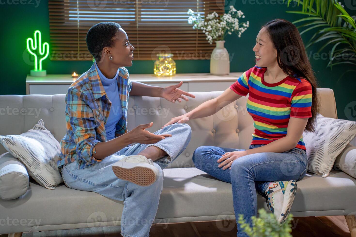 Two women having a conversation while sitting comfortably on a couch photo