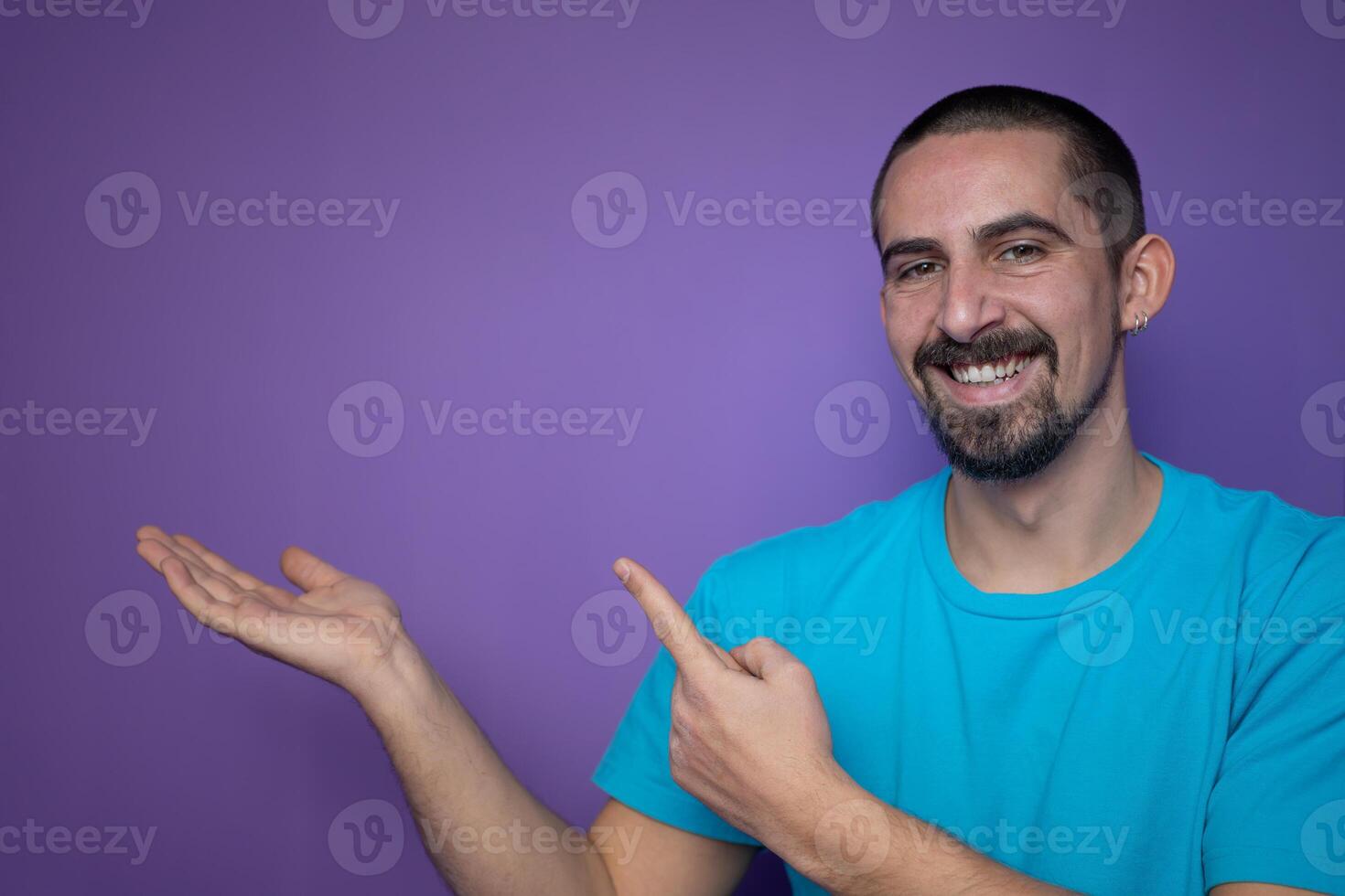 Young man pointing empty space using hands and fingers, isolated over violet background photo