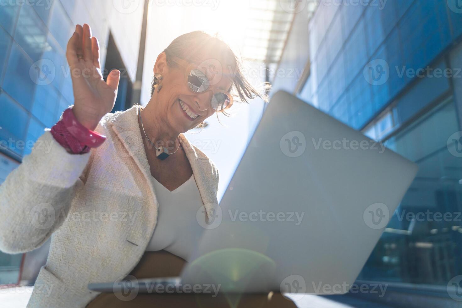 call of a happy attractive business woman middle-aged smiling with laptop in front of a modern building. photo