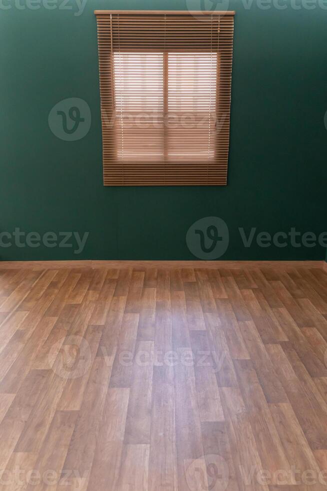 Empty room with wooden flooring, green wall and a window. photo