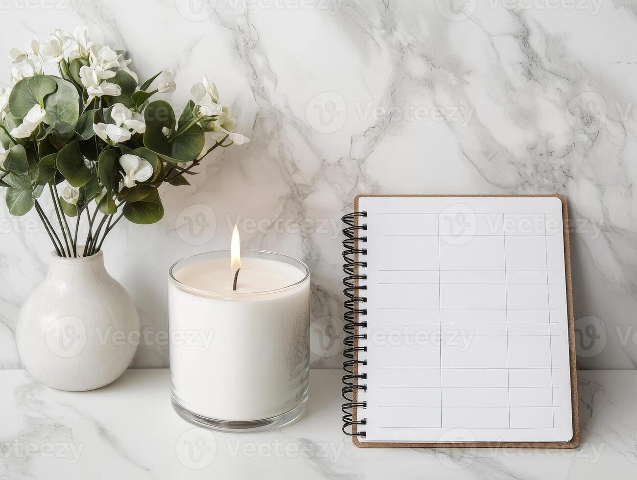 Relaxing setup with a candle, notebook, and flowers on a marble background. photo