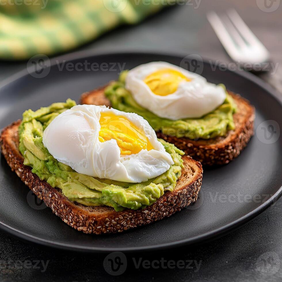 Poached eggs on avocado toast served on a dark plate. photo